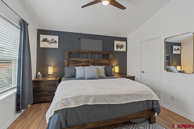 bedroom featuring light wood-style floors, vaulted ceiling, baseboards, and ceiling fan