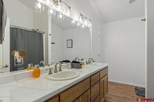 full bathroom with vaulted ceiling, double vanity, wood finished floors, and a sink