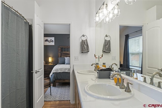 bathroom featuring a sink, double vanity, connected bathroom, and wood finished floors