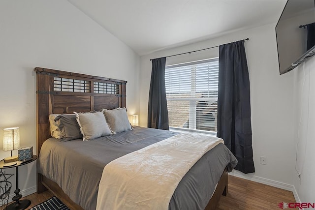 bedroom featuring lofted ceiling, baseboards, and wood finished floors