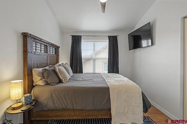 bedroom featuring a ceiling fan, baseboards, vaulted ceiling, and wood finished floors