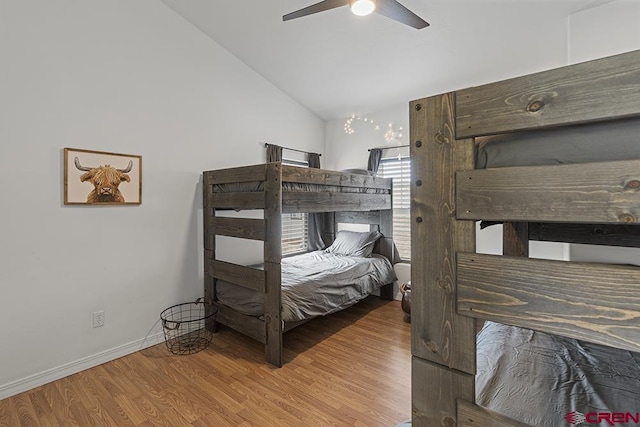 bedroom featuring light wood-style floors, ceiling fan, baseboards, and vaulted ceiling