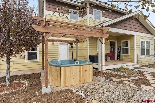 exterior space with a deck, a pergola, and a hot tub