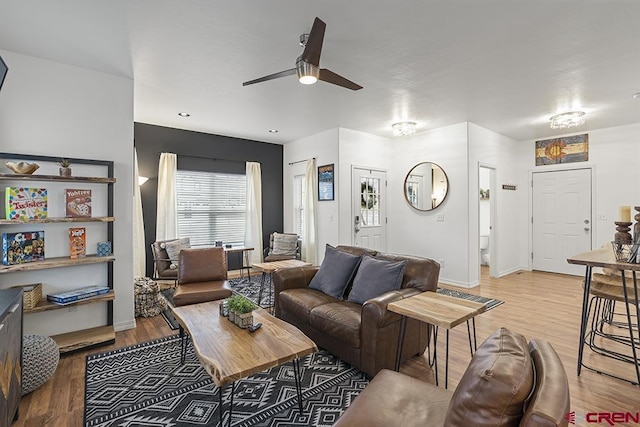 living area with ceiling fan, baseboards, and wood finished floors