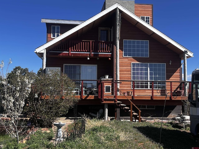 rear view of house featuring a balcony and a wooden deck