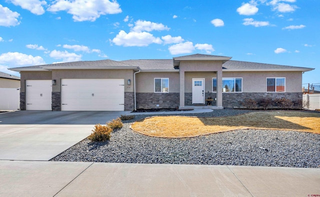 prairie-style house featuring stone siding, driveway, an attached garage, and stucco siding