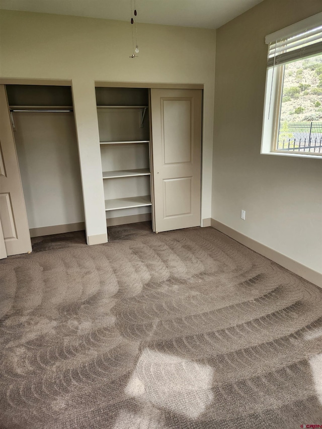 unfurnished bedroom with carpet flooring, baseboards, and two closets