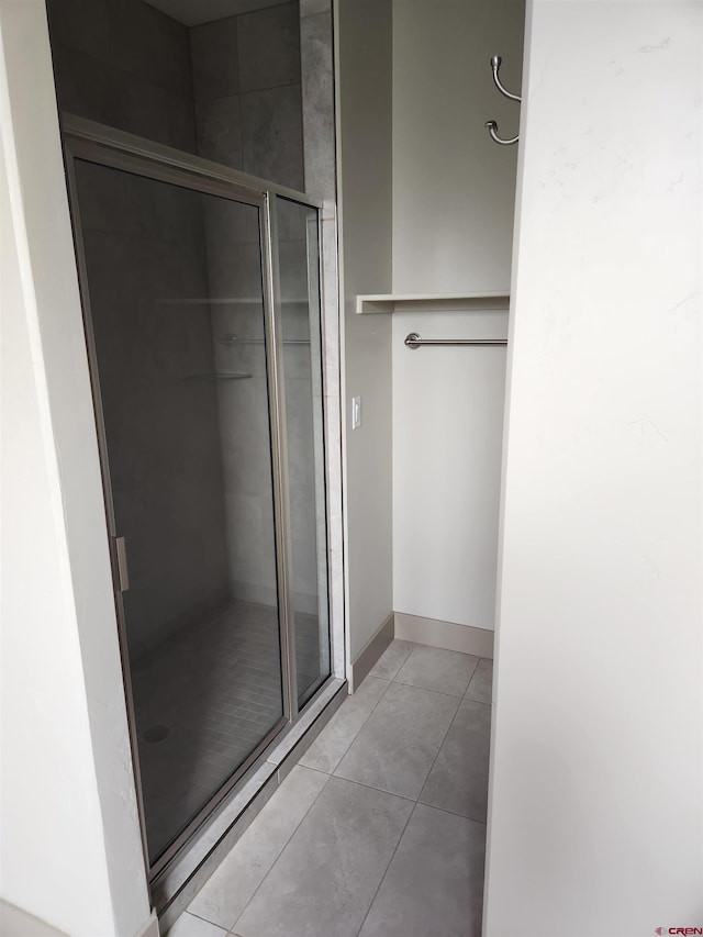 full bath with a shower stall, tile patterned flooring, and baseboards