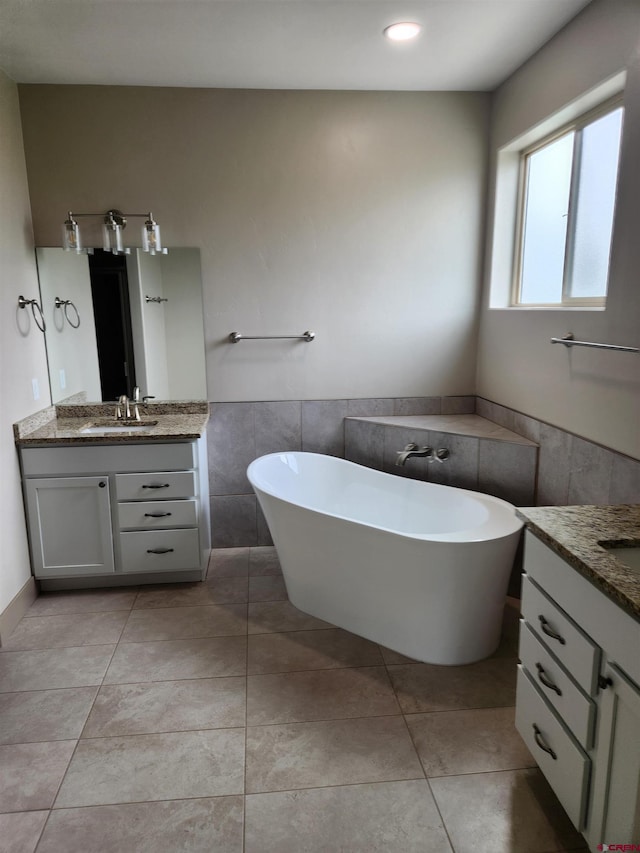 full bath with a wainscoted wall, a soaking tub, two vanities, a sink, and tile patterned floors