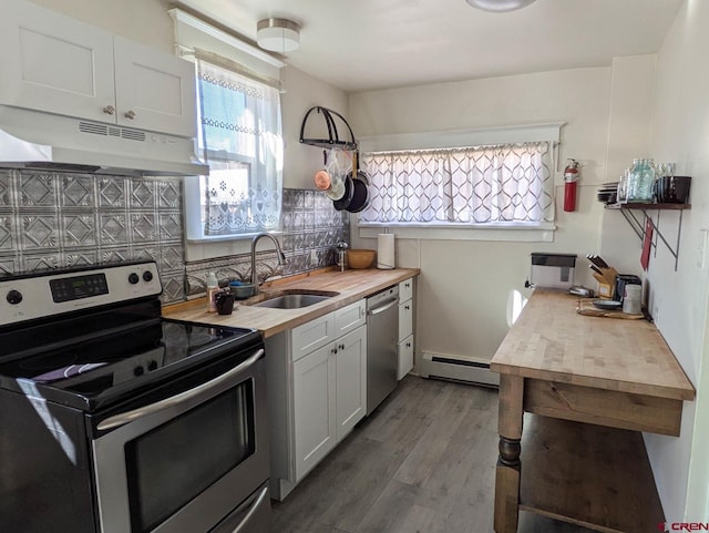 kitchen featuring white cabinets, baseboard heating, stainless steel appliances, under cabinet range hood, and a sink