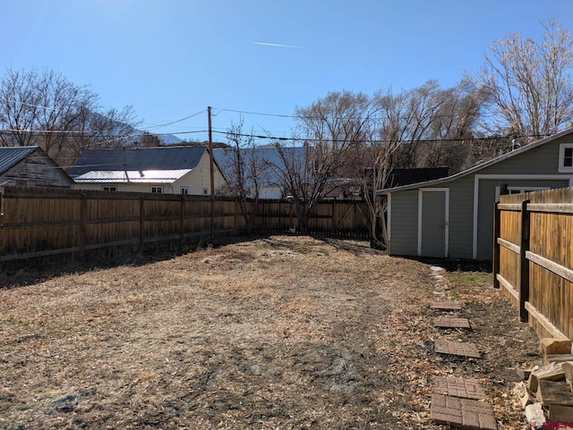 view of yard with a fenced backyard, an outdoor structure, and a storage shed