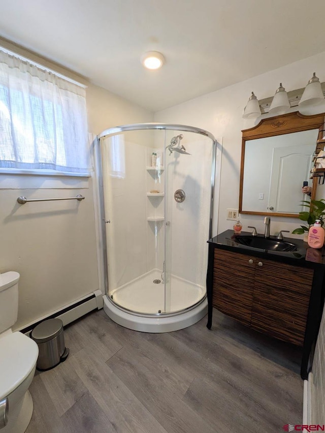 full bath featuring toilet, wood finished floors, vanity, and a shower stall