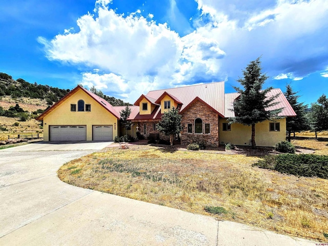 view of front facade featuring stone siding, metal roof, and driveway