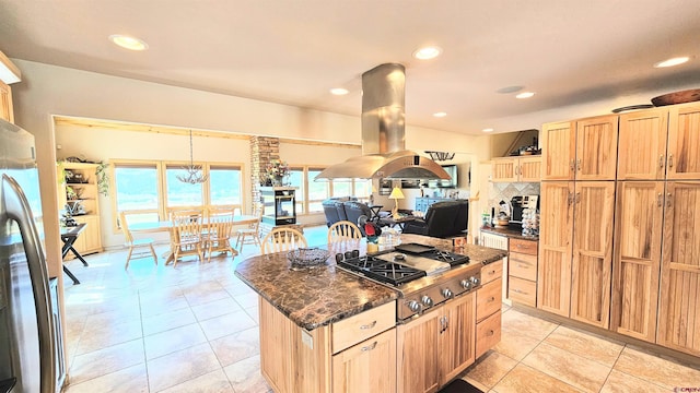 kitchen with decorative light fixtures, island exhaust hood, appliances with stainless steel finishes, a kitchen island, and dark stone counters