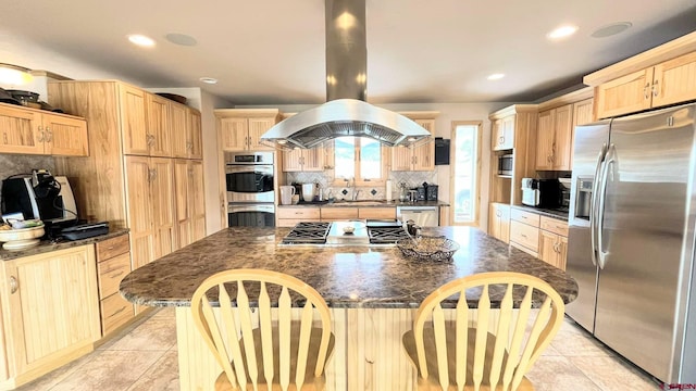 kitchen featuring a breakfast bar, island exhaust hood, stainless steel appliances, decorative backsplash, and dark stone countertops