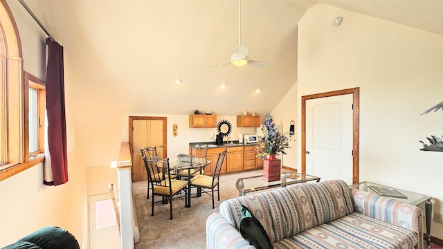 living area featuring high vaulted ceiling, a ceiling fan, and light colored carpet