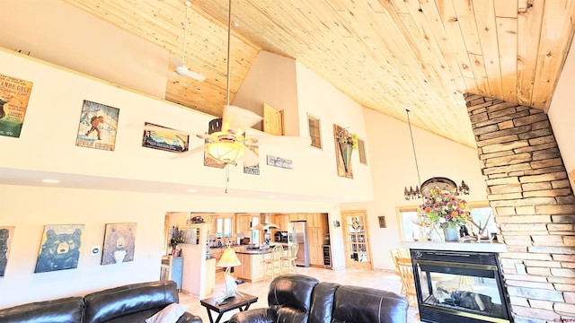 living area with high vaulted ceiling, a stone fireplace, and wooden ceiling