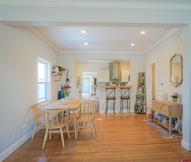 dining space with ornamental molding, light wood-type flooring, and baseboards