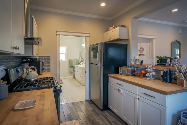 kitchen with crown molding, decorative backsplash, appliances with stainless steel finishes, white cabinets, and butcher block countertops