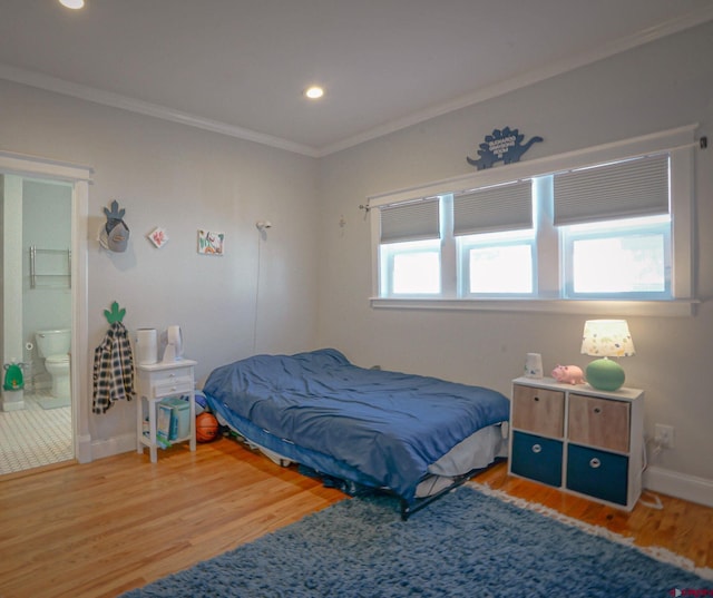 bedroom featuring baseboards, ensuite bath, wood finished floors, crown molding, and recessed lighting