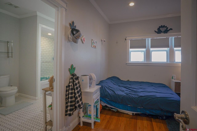 bedroom with baseboards, visible vents, wood finished floors, ensuite bathroom, and crown molding