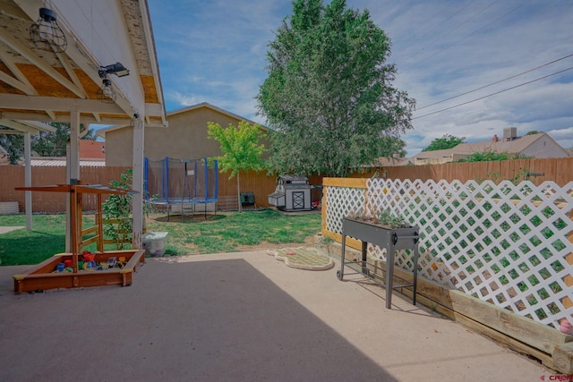 view of patio / terrace with a storage shed, a trampoline, an outdoor structure, and a fenced backyard