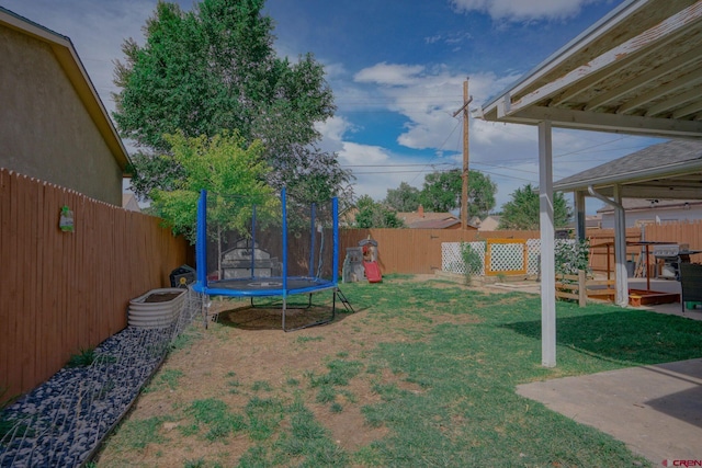 view of yard with a trampoline, a fenced backyard, and a patio