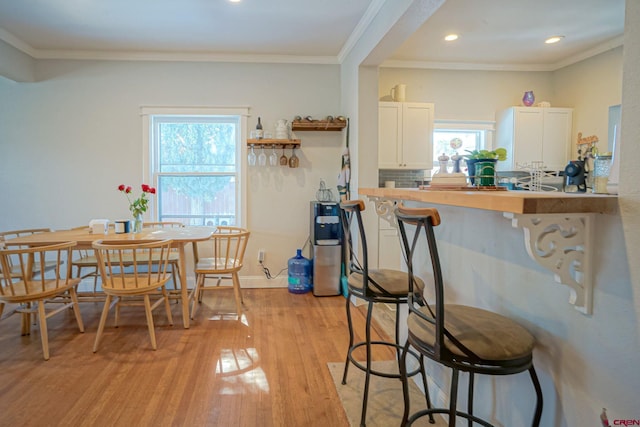 dining room featuring ornamental molding, recessed lighting, light wood-style flooring, and baseboards