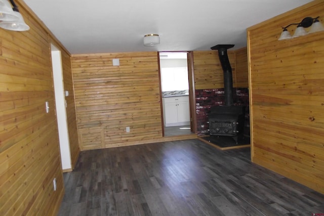 spare room featuring dark wood-style floors, a wood stove, and wooden walls