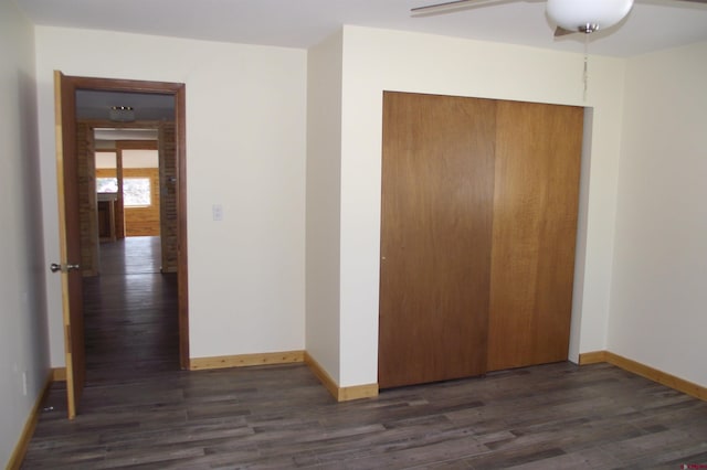 unfurnished bedroom featuring dark wood-type flooring, a closet, ceiling fan, and baseboards