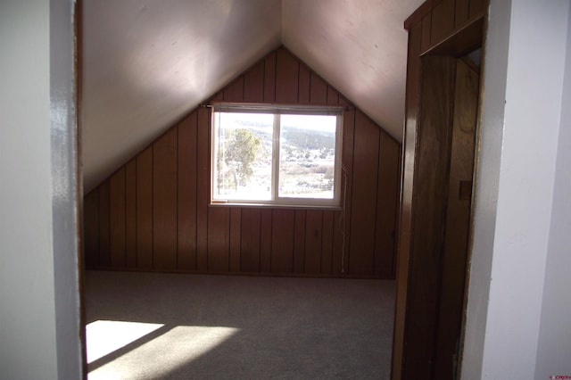 bonus room with vaulted ceiling, carpet floors, and wood walls