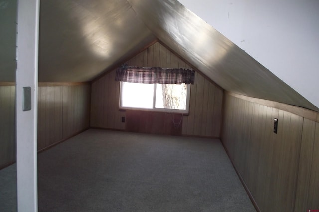 bonus room featuring light carpet, vaulted ceiling, and wood walls