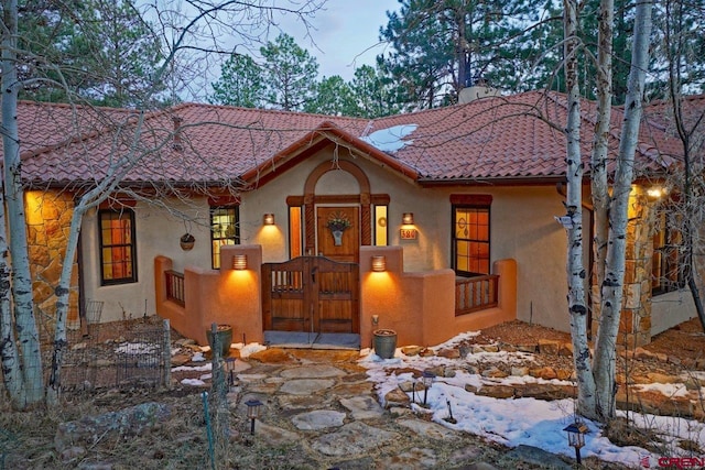 mediterranean / spanish-style house with a gate, a tile roof, fence, and stucco siding