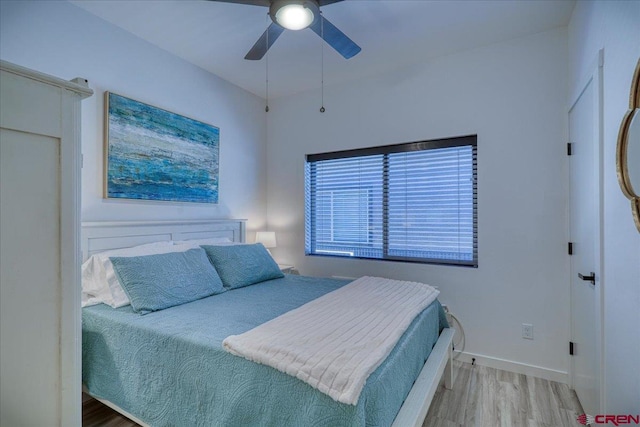 bedroom featuring a ceiling fan, baseboards, and wood finished floors