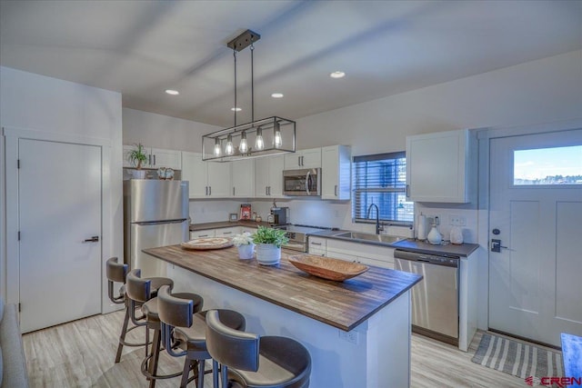 kitchen featuring a center island, pendant lighting, appliances with stainless steel finishes, white cabinetry, and a sink