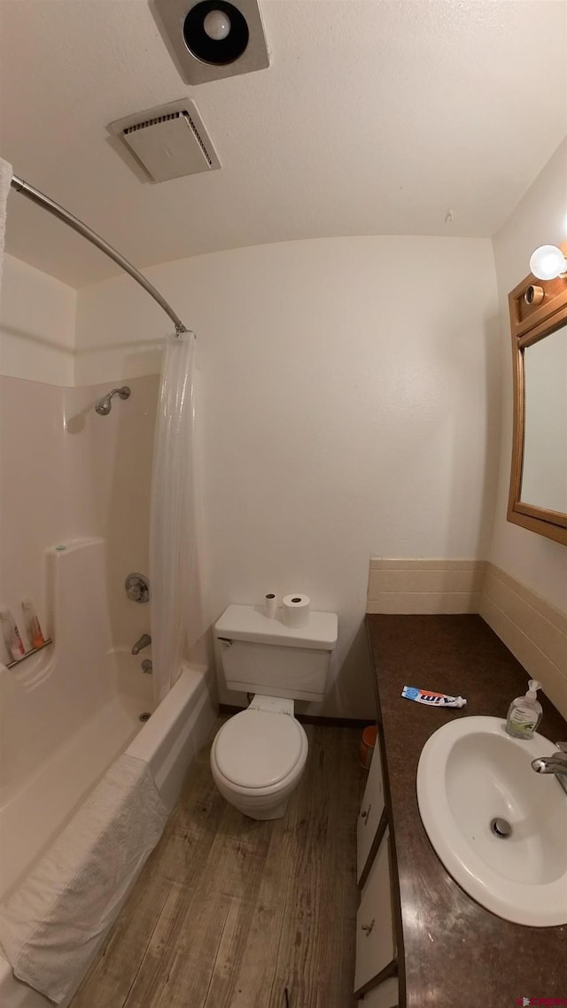 bathroom featuring shower / tub combo with curtain, visible vents, toilet, vanity, and wood finished floors