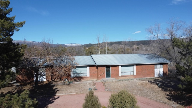 view of front of home featuring metal roof, brick siding, and a mountain view