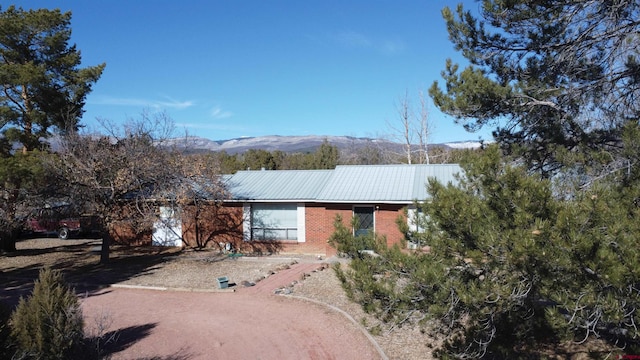 ranch-style home featuring metal roof, brick siding, and a mountain view