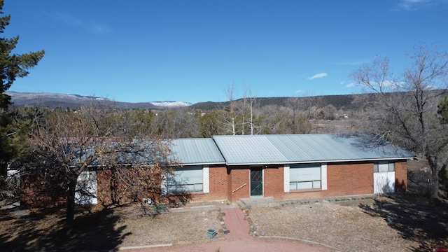 view of front of home featuring metal roof, brick siding, and a mountain view