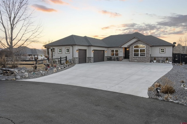 prairie-style house with stone siding, fence, an attached garage, and concrete driveway