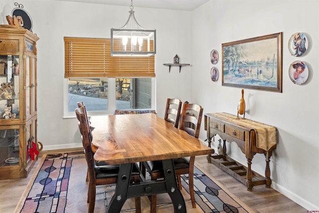 dining space with a notable chandelier, wood finished floors, and baseboards