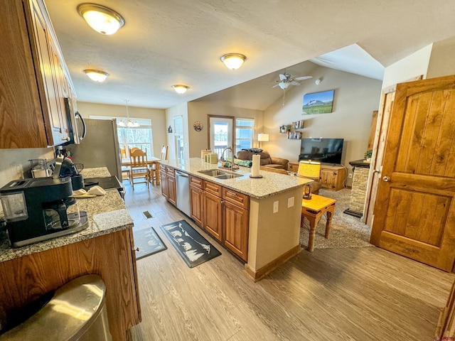 kitchen with brown cabinets, stainless steel appliances, lofted ceiling, light wood-style floors, and a sink