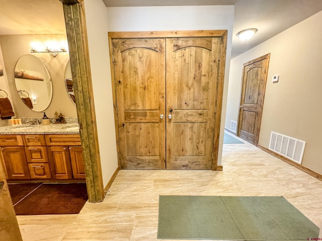 interior space featuring double vanity, a sink, visible vents, and baseboards