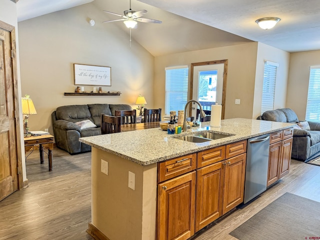 kitchen featuring a kitchen island with sink, a sink, light wood-style floors, open floor plan, and stainless steel dishwasher