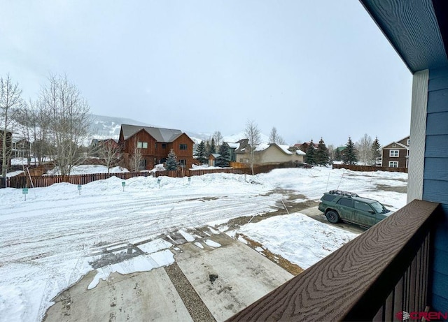 yard layered in snow with a residential view and fence