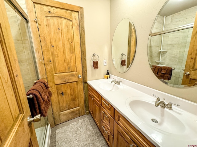 full bath with a shower with shower door, a sink, and double vanity