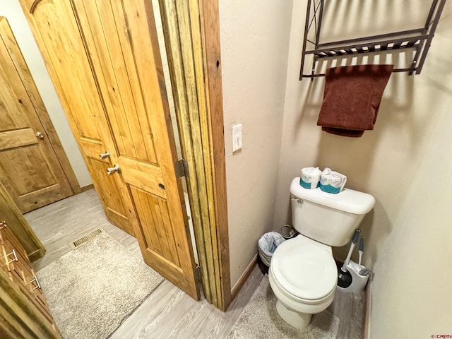 bathroom featuring baseboards, visible vents, toilet, and wood finished floors