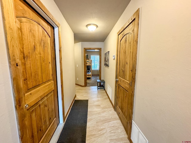 hallway featuring baseboards and visible vents