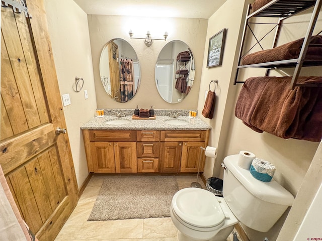 bathroom featuring toilet, double vanity, and a sink