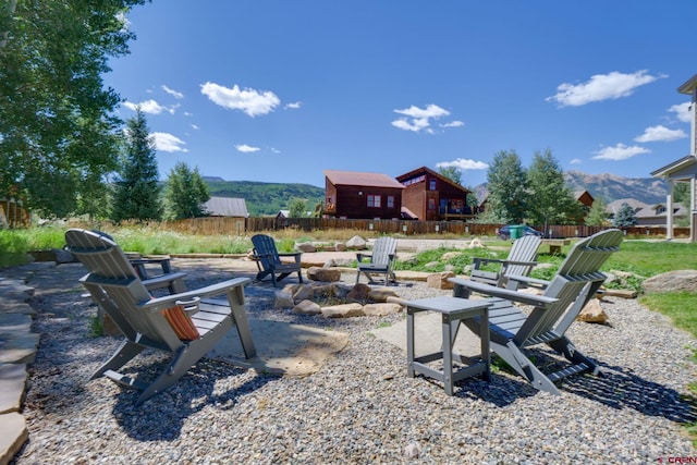 view of patio / terrace featuring an outdoor fire pit, fence, and a mountain view